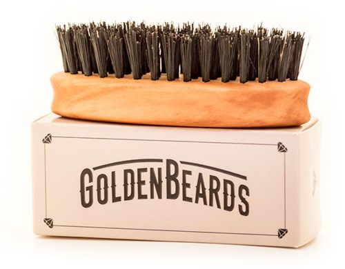 En skoborste med svart borst ligger på en låda som heter 'GOLDEN BEARDS'.