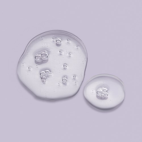 Two clear, gel-like blobs with bubbles on a plain purple background.