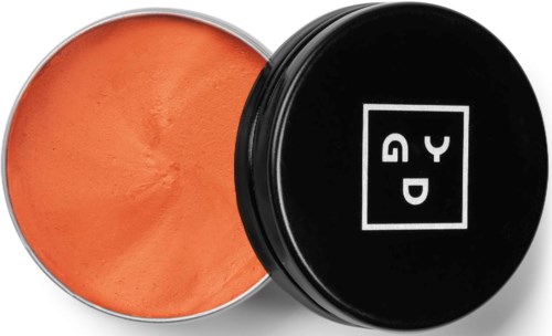A round container with orange powder inside and a black lid with white logo on it.