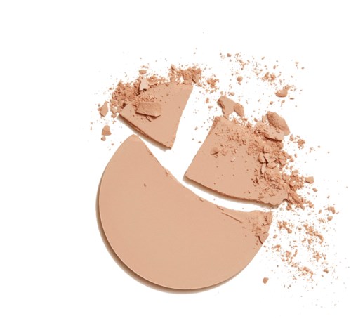 En rund, beige makeuppudder med to knuste stykker og spredt pudder omkring.