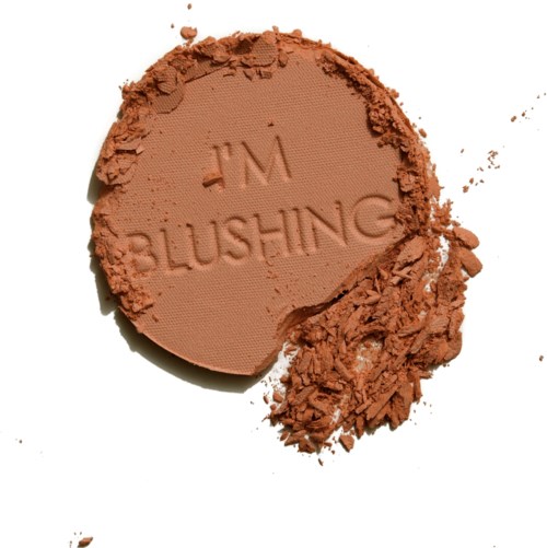 Ein runder Make-up-Puder mit dem Wort 'BLUSHING' eingraviert und etwas Puder darum.