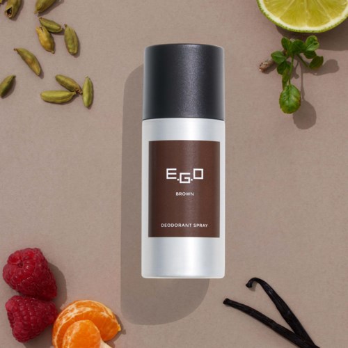 Deodorantenspray mit schwarzem Deckel, gekennzeichnet E.G.O BROWN, auf beiger Oberfläche mit Limette, Beeren, Kardamom und Vanille.
