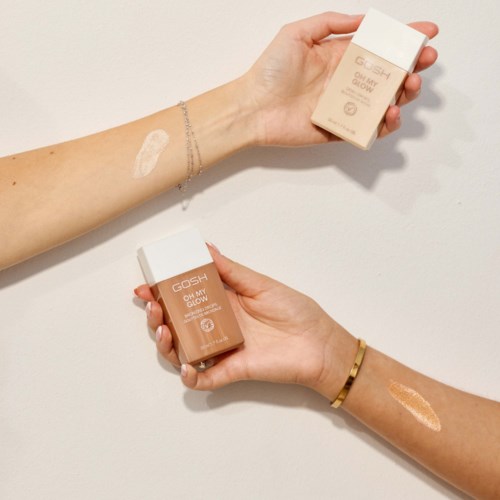 Two arms show swatches of GOSH skincare products, one in a light shade and the other in a darker shade.