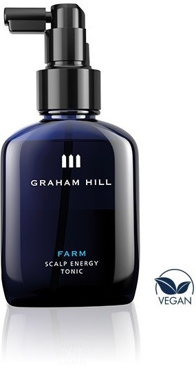 En mørk blå flaske med pumpe. Den har orden 'GRAHAM HILL' og 'FARM SCALP ENERGY TONIC'. En vegansk etikett er på den.