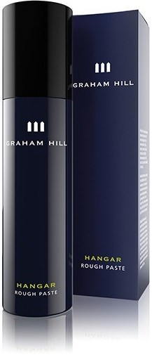 En mörkblå och svart sprayburk med vit och gul text, bredvid sin matchande låda, märkt Graham Hill Hangar Rough Paste.