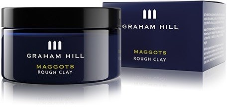 Et mørkblåt glas med sort låg og en blå æske, begge mærket Graham Hill Maggots Rough Clay.