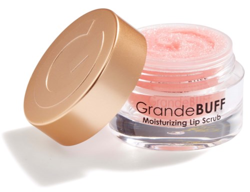 En liten rund burk med rosa läppskrubb och ett guld lock bredvid.