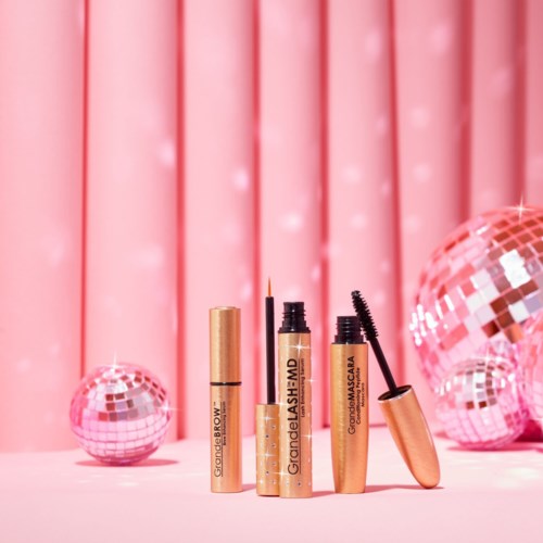 Lip gloss, mascara, and lip brush on pink background with disco balls. Elegant and shiny makeup items displayed nicely.