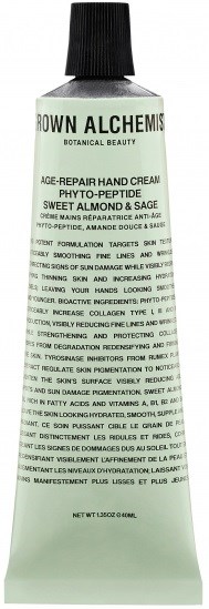 En tub med handkräm märkt 'CROWN ALCHEMIS' innehåller ingredienser för hudreparation och anti-aging fördelar.