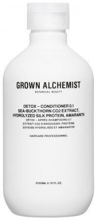 En vit flaska med svart text, märkt GROWN ALCHEMIST, innehållande detoxbalsam med botaniska ingredienser.