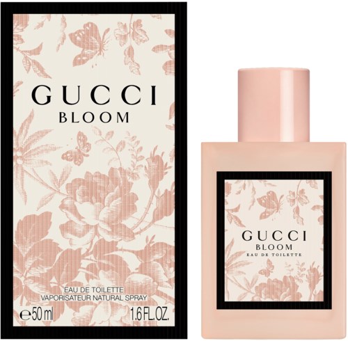 Billedet viser en lyserød parfuebæger og æske til Gucci Bloom, med blomster- og sommerfugldesigner.