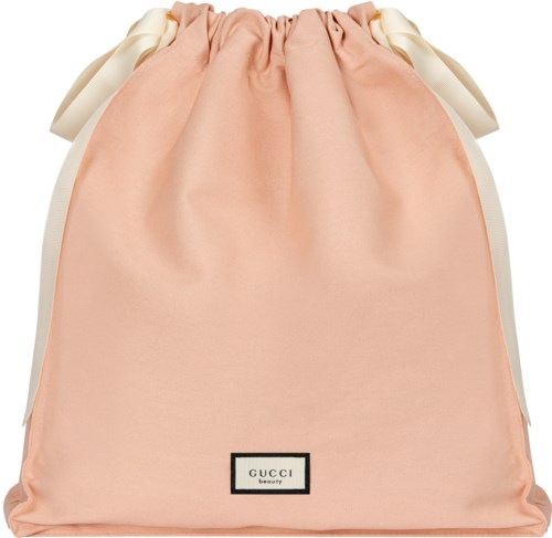 En ljusrosa väska med vita band på sidorna och ett Gucci beauty-märke längst ner.