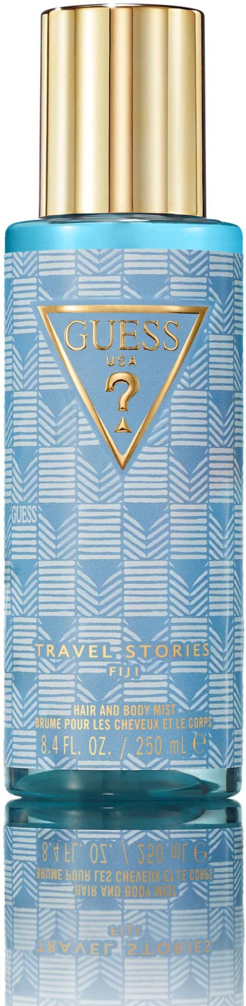 Blå flaske med gullhette, merket Guess Travel Story, inneholder hår- og kroppsspray.