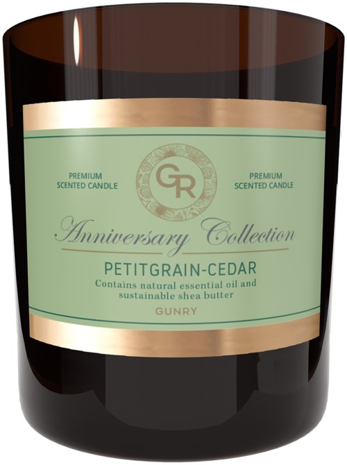 Musta kynttilänjalka, jossa on vihreä ja kultainen etiketti, joka kertoo Anniversary Collection Petit Grain Cedar tuoksukynttilästä.