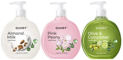 Tre flytande tvålpumpar med etiketter för mandelmjölk, rosa pion och olivgurka, placerade sida vid sida.