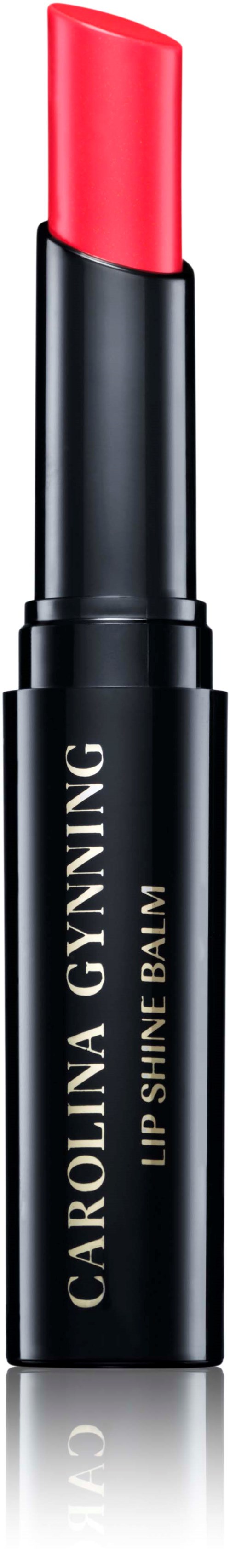 Ett svart rör med guldtitlar innehåller ett ljust rosa läppbalsam. Produkttiteln är Carolina Gynning Lip Shine Balm.