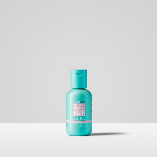 En liten turkis flaske med hårprodukt med rosa og hvit etikett, står alene på en enkel bakgrunn.