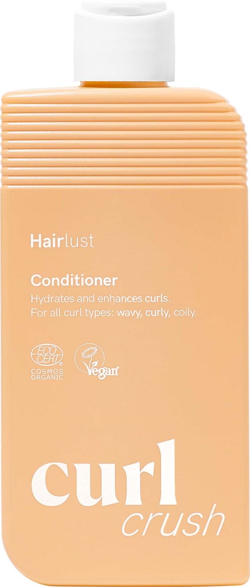 Perzikkleurige fles met Hairlust curl crush conditioner, witte dop en getextureerde bovenkant, geschikt voor hydrateren en verbeteren van krullen.