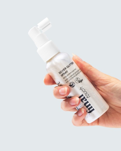 Een hand houdt een kleine sprayfles met label Silver Glitter Spray voor make-up of knutselgebruik.