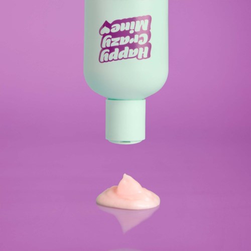 En flaske mærket "Happy Crazy Cream" er omvendt og frigiver pink cremen på en lilla overflade.