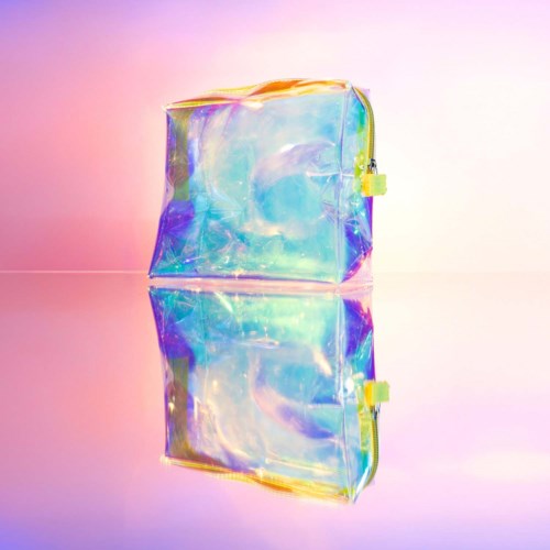 En glänsande, holografisk väska med dragkedja som reflekterar pastellfärger. Den är placerad på en reflekterande yta med en pastellbakgrund.