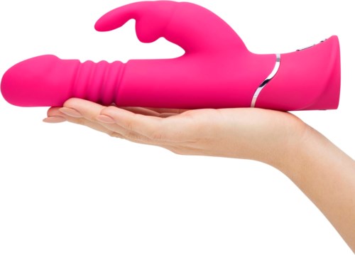Een roze, gebogen, op afstand bedienbare speelgoedhand op een mensenhand. Het is gevormd als een hand met vingers. Compact en glad.