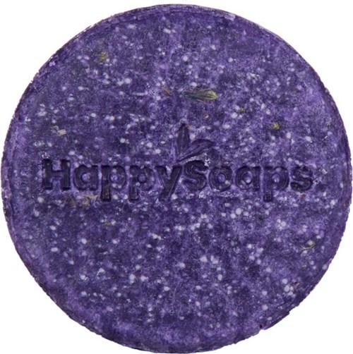En lila badbomb med fläckar och texten 'Happy Soaps' inristat. Den är rund och grov.