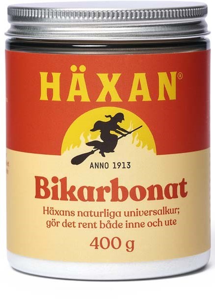 En röd och krämfärgad burk med märket 'HÄXAN Bikarbonat' och en häxsilhuett med text om dess naturliga användning.