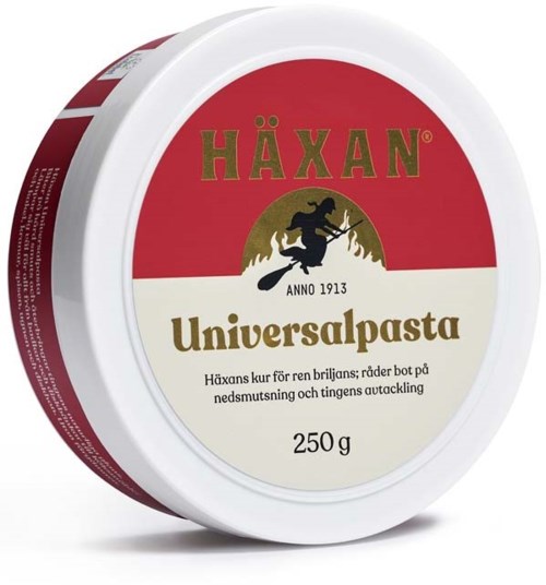 En rund behållare med röd och vit etikett. Den står "Häxan" och "Universalpasta," med en svart häxa som rider på en kvast.