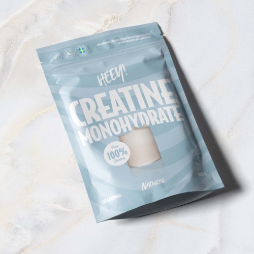 En ljusblå förpackning märkt 'Creatine Monohydrate' med en tydlig skopa och naturliga ingredienser.