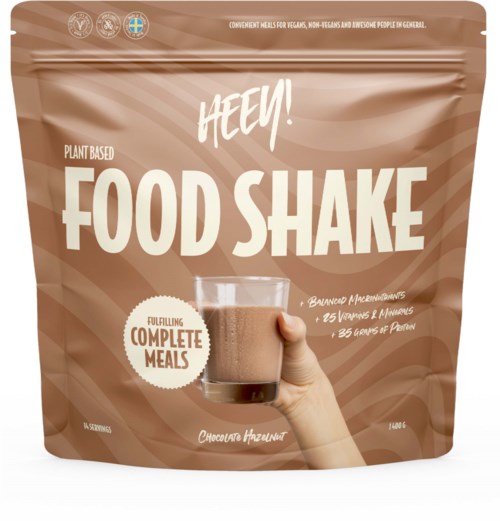En brun påse med ett glas chokladdrink, märkt "HEEY! FOOD SHAKE" för växtbaserade kompletta måltider.