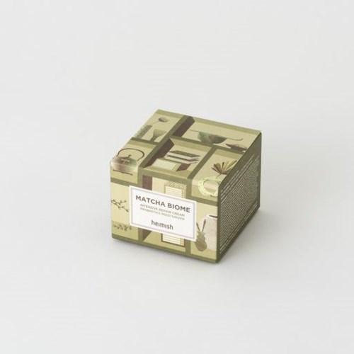 En liten, dekorativ låda med gröna och beige växt- och naturbilder. Den har en etikett som säger "Matcha Biome."