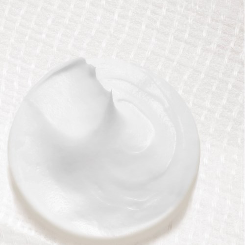 A dollop of white cream or yogurt on a surface, with a rounded, peaked shape.