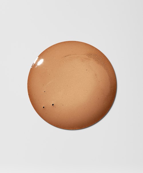 Et brunt egg med to små svarte flekker, lysrefleks øverst til venstre, på en enkel hvit bakgrunn.