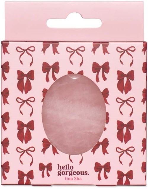 Rosa presentask med röda rosettmönster och ett genomskinnligt ovalt fönster, märkt Hello Gorgeous Gua Sha.
