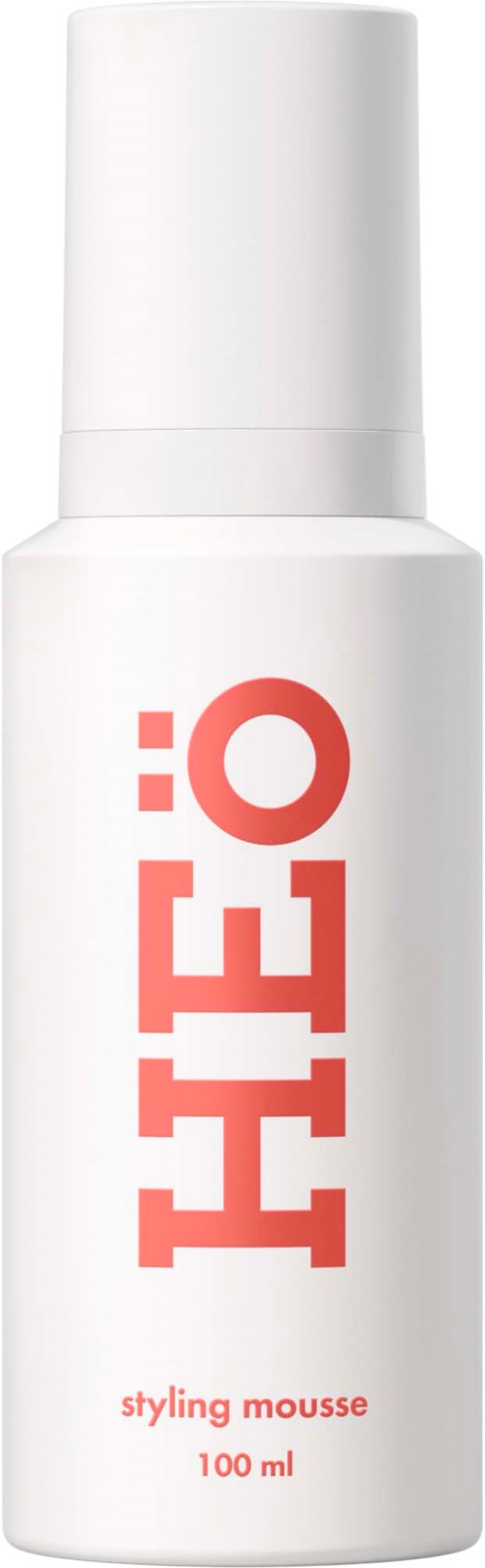 Een witte fles met grote rode letters die 'HEILO' spellen en kleine tekst 'styling mousse 100 ml'.