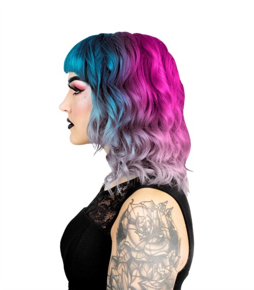 Eine Frau mit Regenbogenfarbenem Haar in Blau, Pink und Grau, und einem Tattoo am Arm.