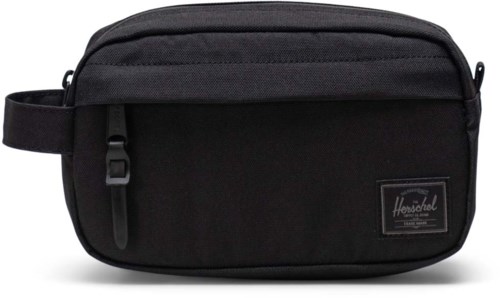 A black toiletry bag with a zipper pocket, handle, and a Herschel logo patch. It looks portable and organized.