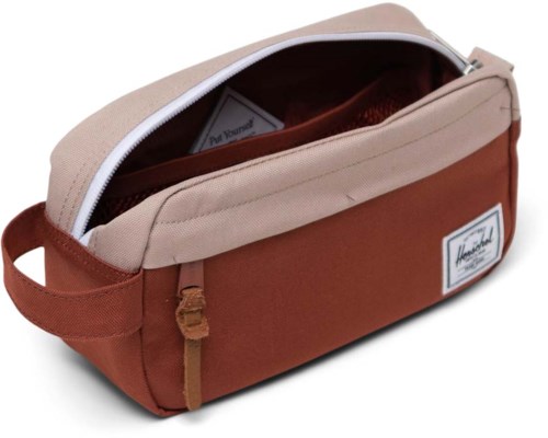 A bag with a beige top and brown bottom, zipper open showing an interior pocket, label on front, handle on side.
