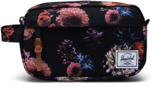 A floral patterned black bag with a small label, zipper, and side strap. It has colorful flowers in pink, purple, and blue.