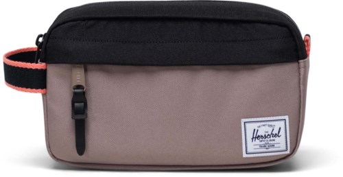 A small bag with a black top, beige bottom, and a red strap. It has a zipper and a label that says Herschel.