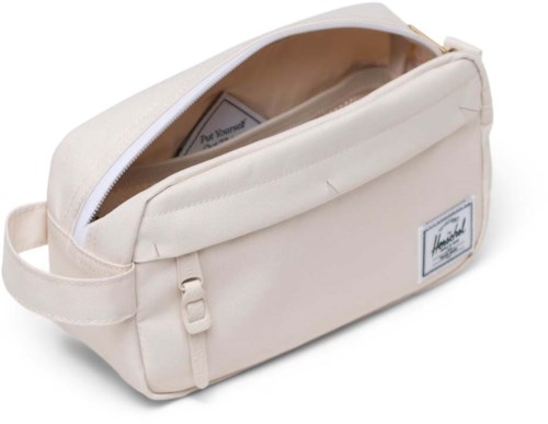 A cream-colored bag with a zipper open, revealing a small book inside, and a label on the front.