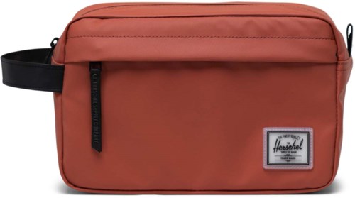 En korallfärgad väska med svart handtag, dragkedjeficka och Herschel-logotyp.