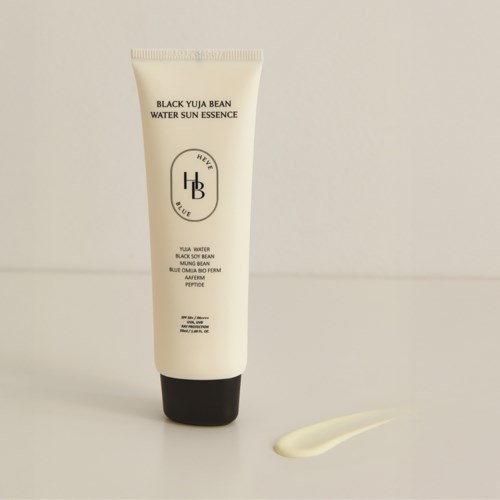 En vit tub med svart lock visar en hudvårdsprodukt som heter Black Yuja Bean Water Sun Essence. En liten mängd pressas ut bredvid.