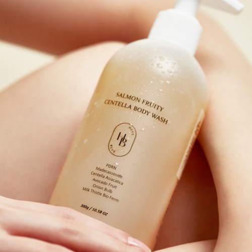 En flaske Salmon Fruity Centella Body Wash på en persons legget med annen hud synlig.