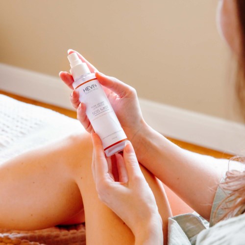 Osoba nakładająca lotion lub krem na ramię za pomocą sprayu w domu.