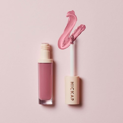En rosa leppglans med en svanformet tupp og en rosa hette med merkenavnet 'HICKAP' på en lys rosa bakgrunn.