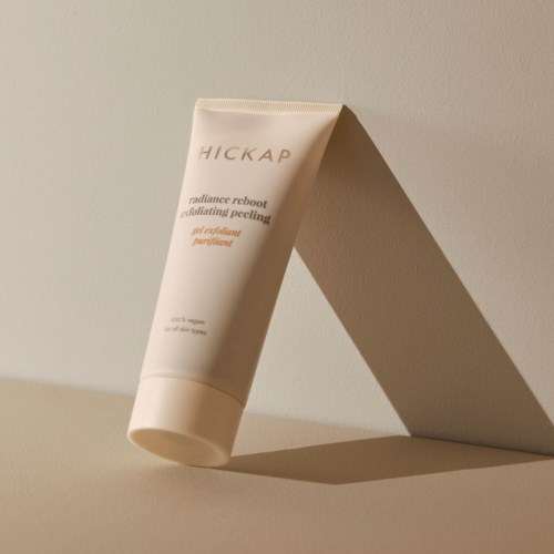 En tube merket 'HICKAP' med produktdetaljer, står mot en enkel bakgrunn med skygge.