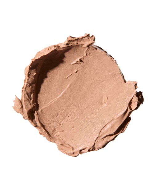 En rund, beige, krämig substans utbredd på en vit bakgrund. Det ser ut som en kosmetik- eller hudvårdsprodukt.