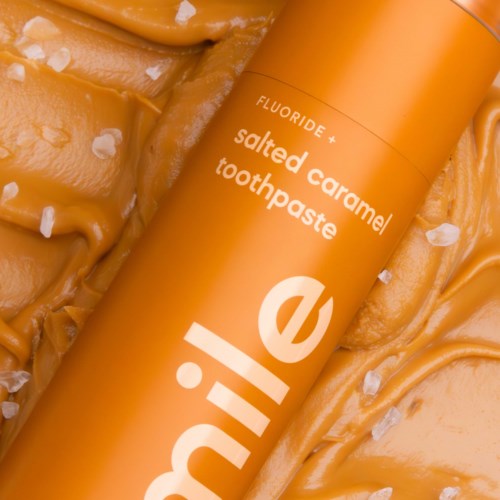 En lys orange tandpastatube med 'salted caramel' tekst og saltflager omkring den.